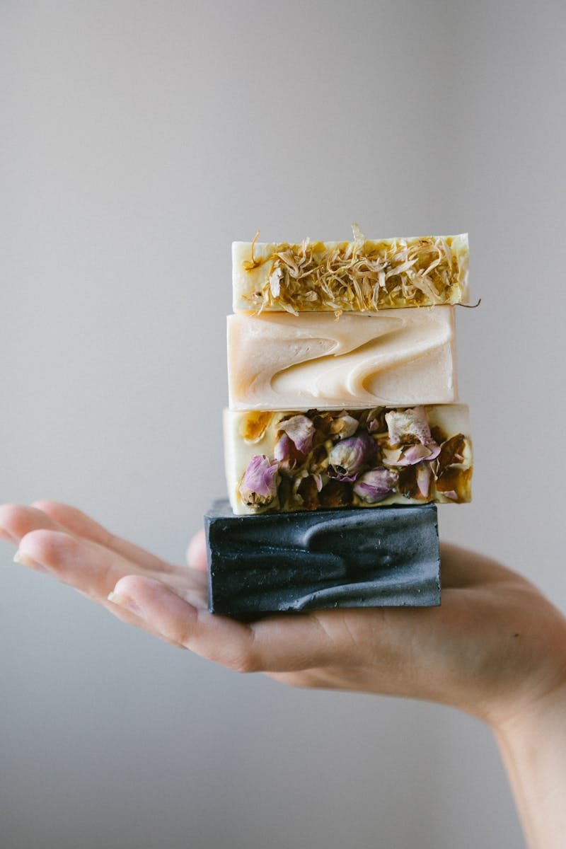 Stack of handmade organic soaps enhanced with dried flowers on an open hand.